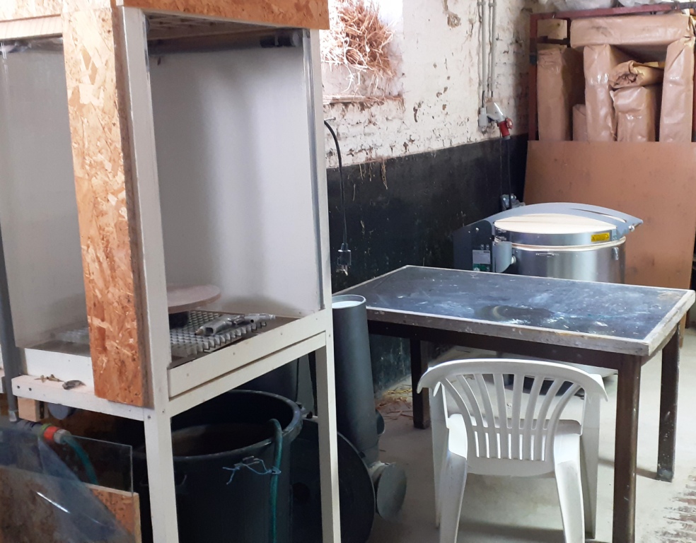 la cabine d'émaillage (pour émailler les pièces biscuitées au préalable) et dans le fond on aperçoit le four électrique indispensable aux céramistes